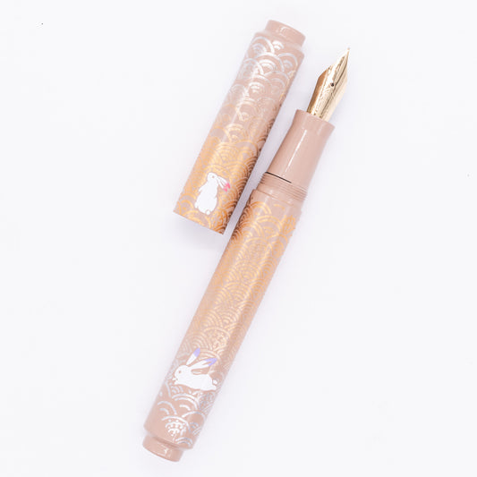 An overhead view of the AP Limited Editions Sakura Lacquer Art Fountain Pen - Rabbits in a Summer Garden uncapped, with the cap next to the body angled towards the right.