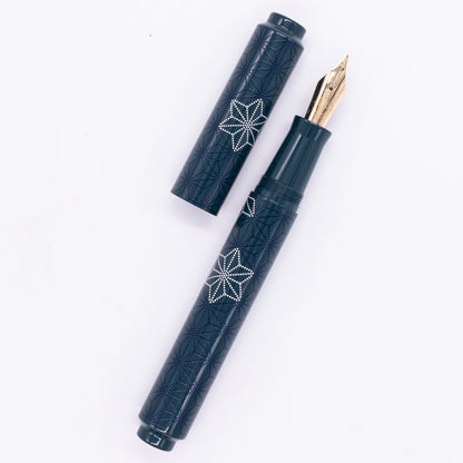 An overhead view of the AP Limited Editions Sakura Lacquer Art Fountain Pen - Snowflakes Blue uncapped, with the cap next to the body angled towards the right.