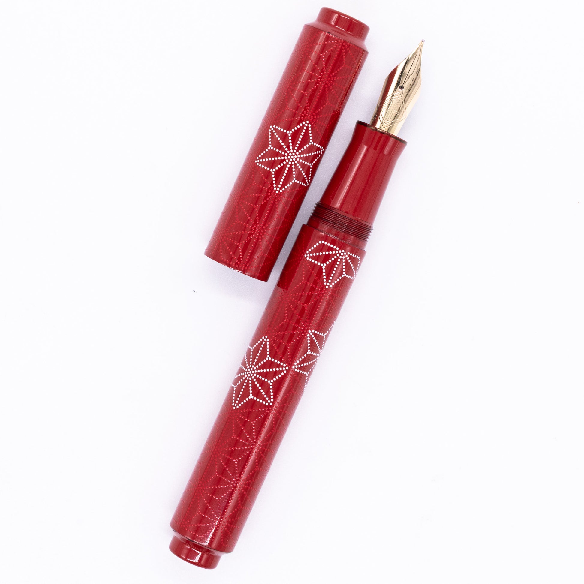 An overhead view of the AP Limited Editions Sakura Lacquer Art Fountain Pen - Snowflakes Red uncapped, with the cap next to the body angled towards the right.