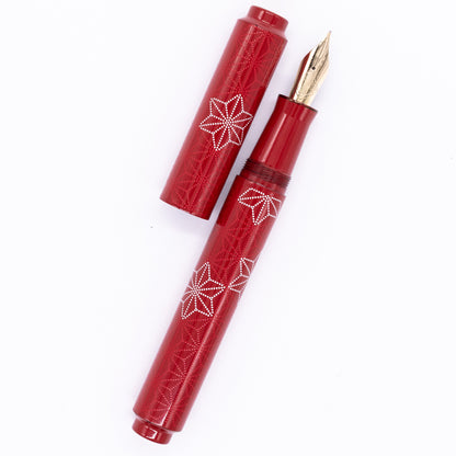An overhead view of the AP Limited Editions Sakura Lacquer Art Fountain Pen - Snowflakes Red uncapped, with the cap next to the body angled towards the right.