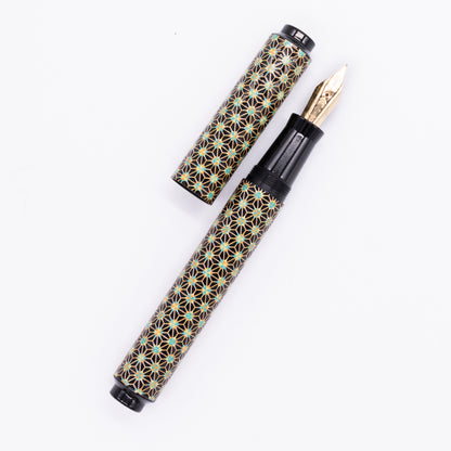 An overhead view of the AP Limited Editions Sakura Lacquer Art Fountain Pen - Teal Stars uncapped, with the cap next to the body angled towards the right.