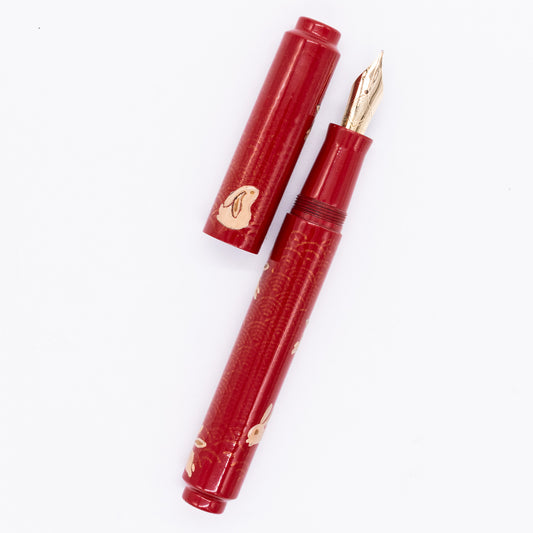 An overhead view of the AP Limited Editions Sakura Lacquer Art Fountain Pen - Year of the Rabbit uncapped, with the cap next to the body angled towards the right.