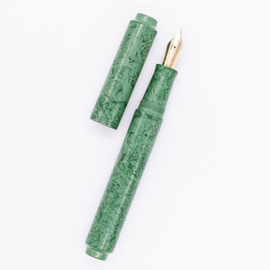 An overhead view of the AP Limited Editions Urushi Lacquer Art Fountain Pen - Celadon Moss uncapped, with the cap next to the body angled towards the right.