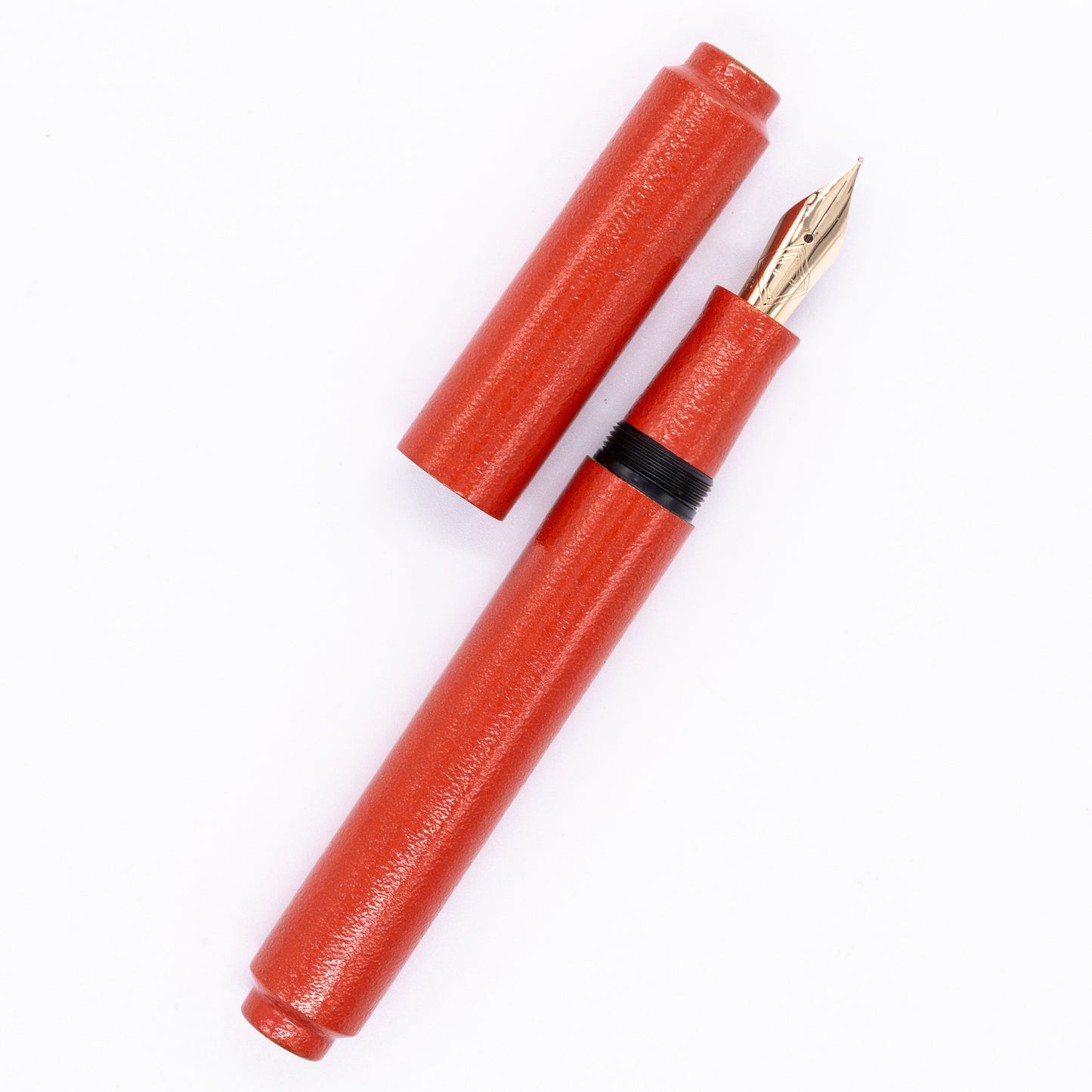 An overhead view of theAP Limited Editions Urushi Lacquer Art Fountain Pen - Colors of the Cosmos Aldebaran uncapped, with the cap next to the body angled towards the right.