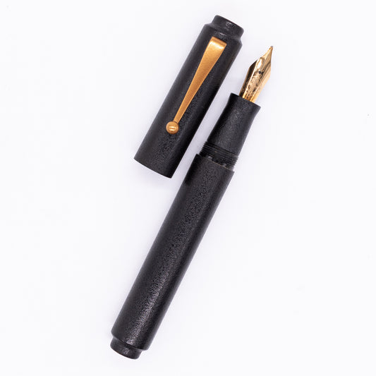 An overhead view of the AP Limited Editions Urushi Lacquer Art Fountain Pen - Ishiji Black & Gold uncapped, with the cap next to the body angled towards the right.