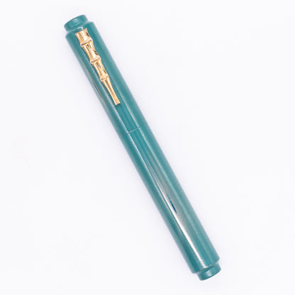 An overhead view of the AP Limited Editions Urushi Lacquer Art Fountain Pen - Proplyd Aqua (with Bamboo Clip) capped, angled towards the left.
