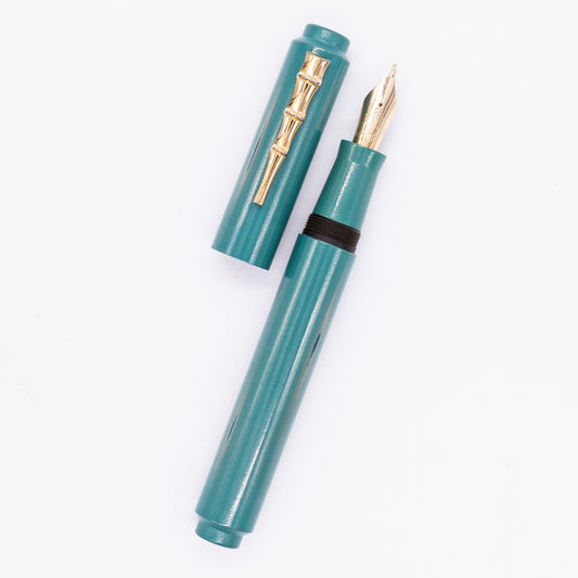An overhead view of the AP Limited Editions Urushi Lacquer Art Fountain Pen - Proplyd Aqua (with Bamboo Clip) uncapped, with the cap next to the body angled towards the right.