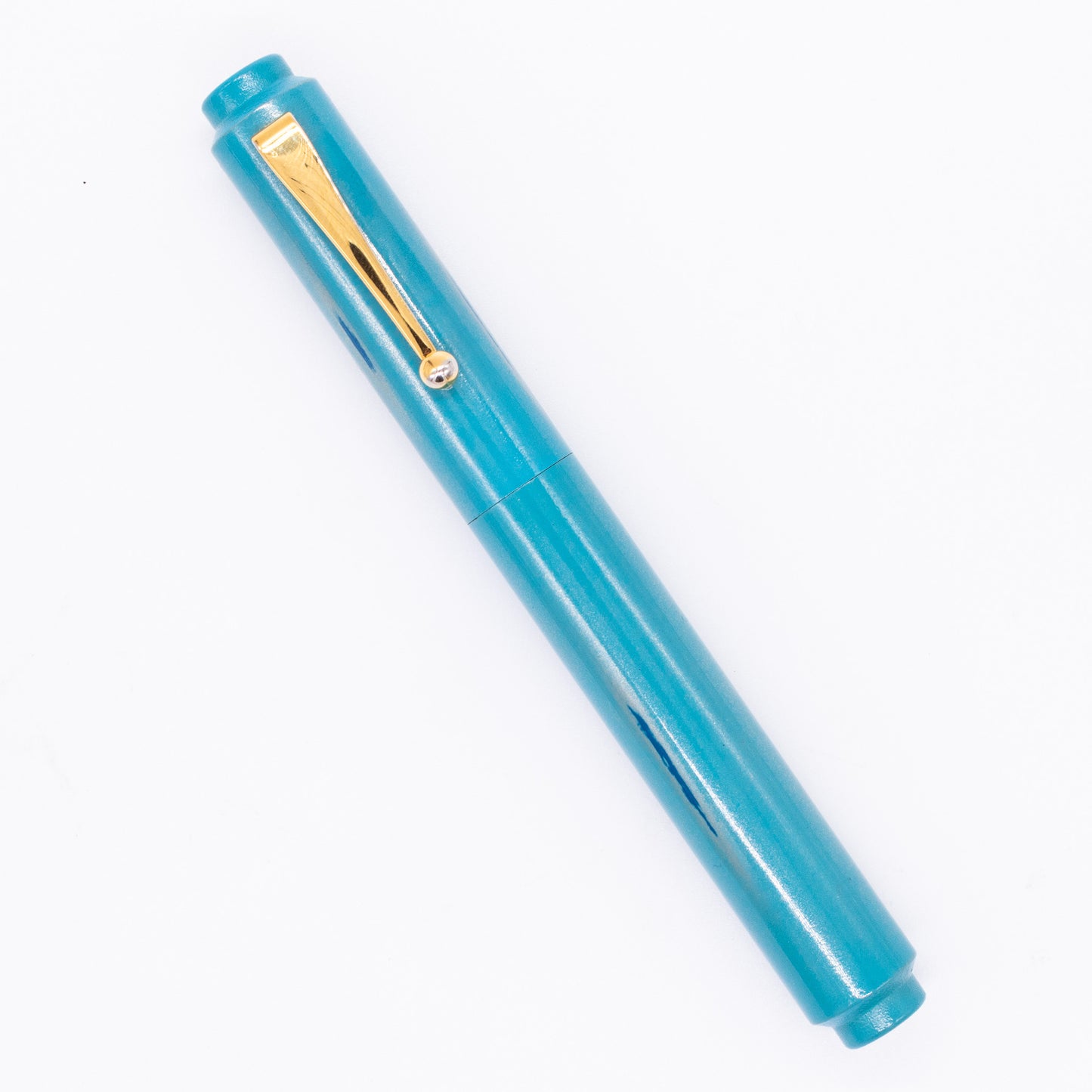 An overhead view of the AP Limited Editions Urushi Lacquer Art Fountain Pen - Proplyd Aqua capped, angled towards the left.