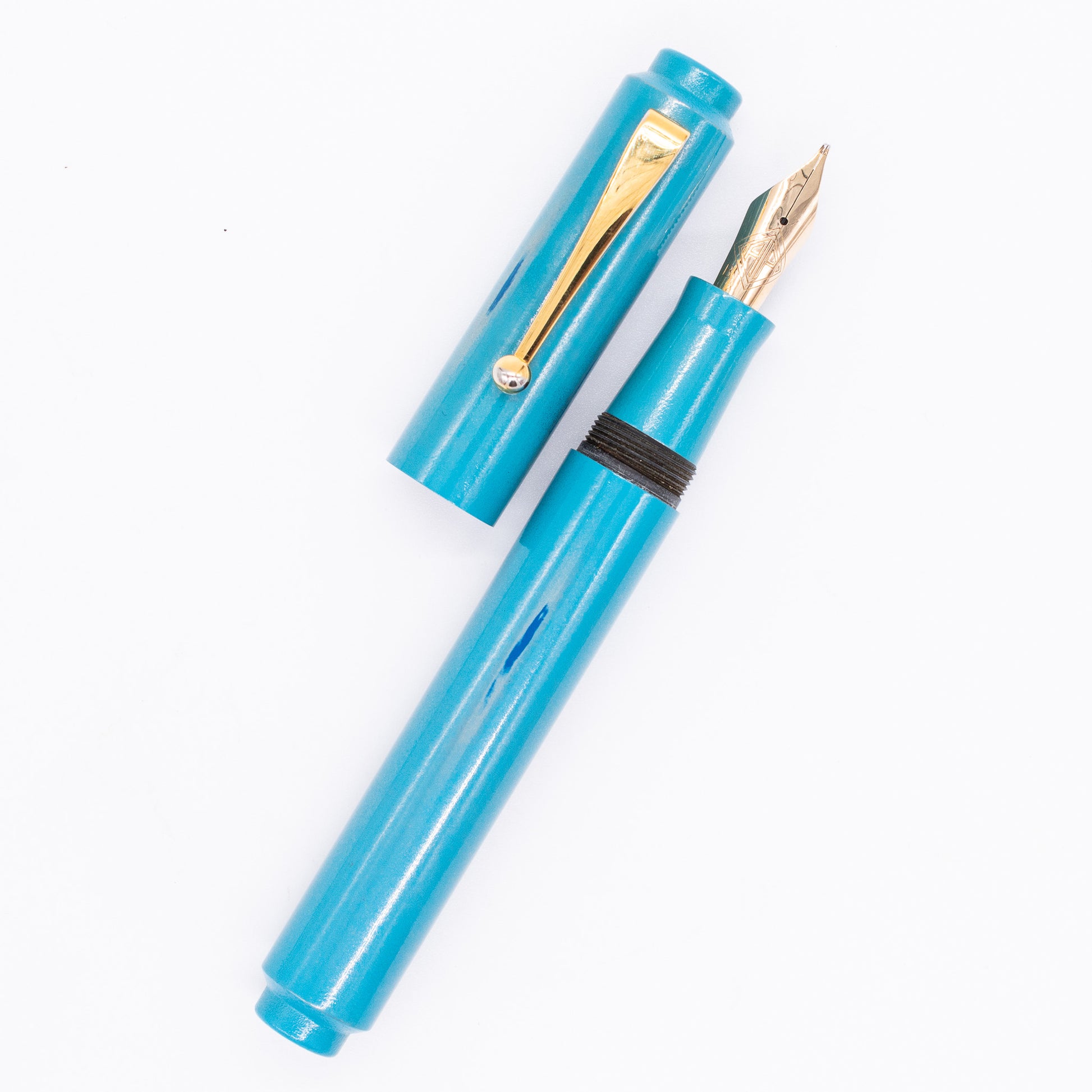 An overhead view of the AP Limited Editions Urushi Lacquer Art Fountain Pen - Proplyd Aqua uncapped, with the cap next to the body angled towards the right.