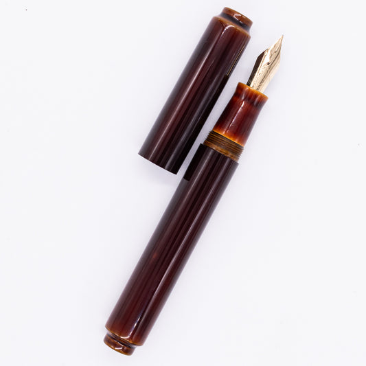  An overhead view of the AP Limited Editions Urushi Lacquer Art Fountain Pen - Tamenuri Yellow uncapped, with the cap next to the body angled towards the right.